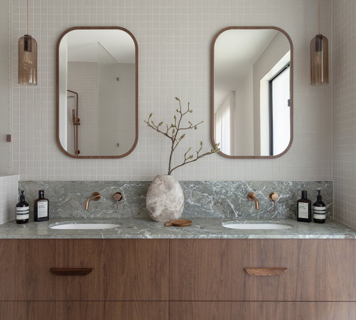 A bathroom with brushed-brass wall mixers, timber vanity and stone benchtop